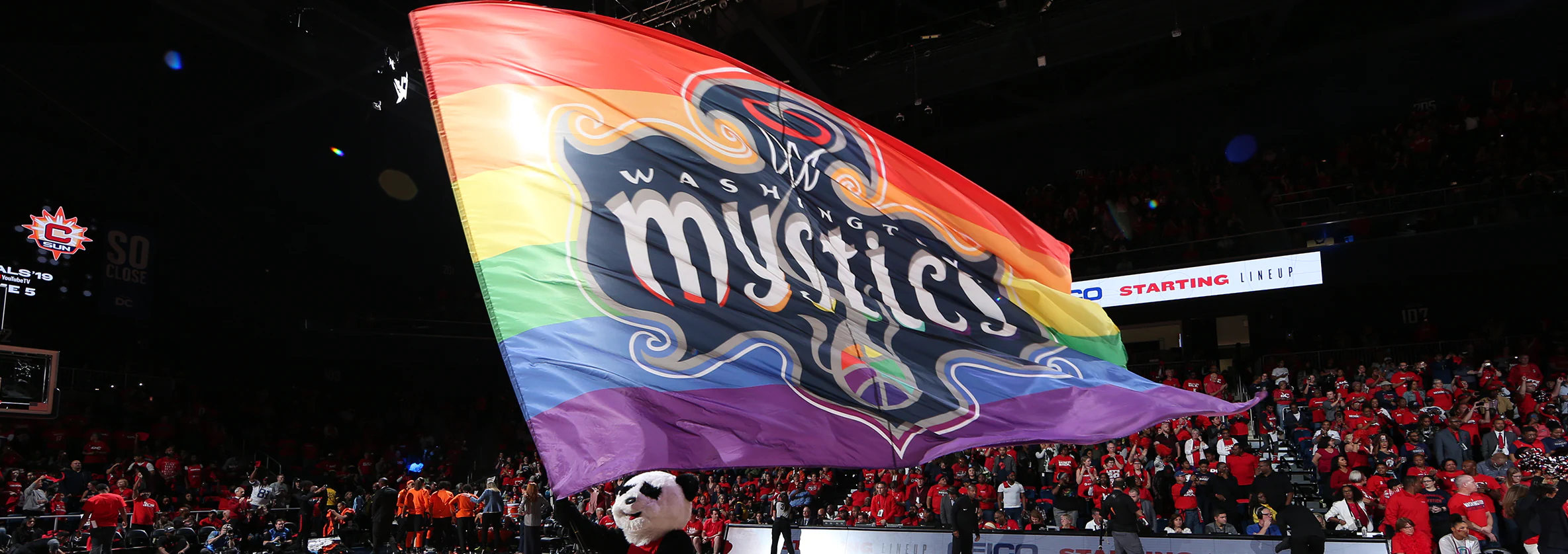 Large pride flag with the Washington Mystics logo flown at WNBA game